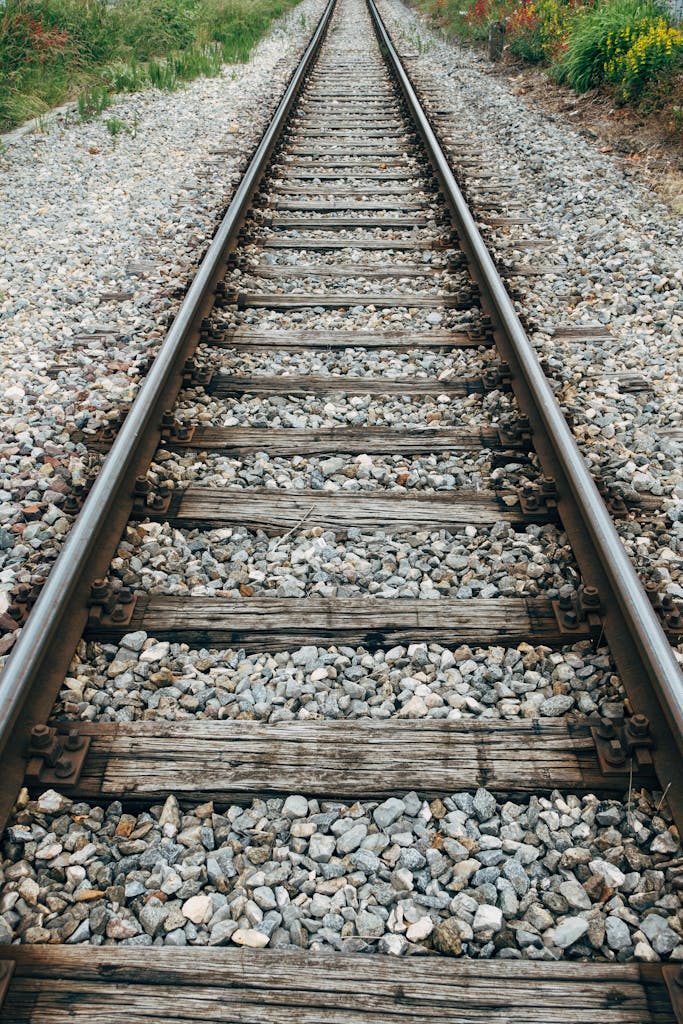 A rustic railway track extends into the distance with wooden sleepers and gravel ballast.